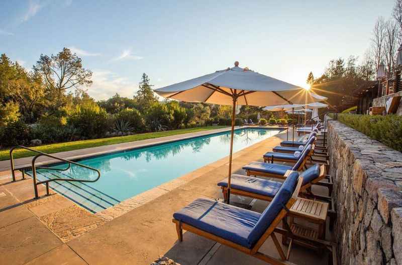 a pool with blue lounge chairs and an umbrella
