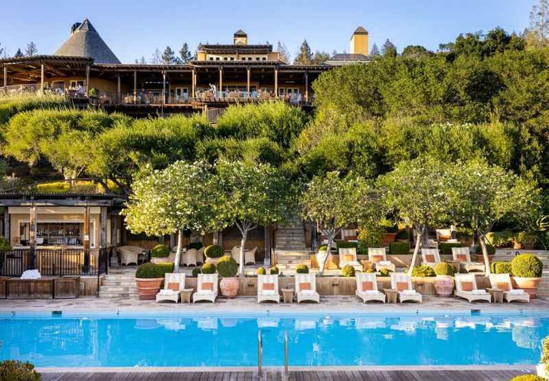 Facade of  resort covered with trees and pool in front