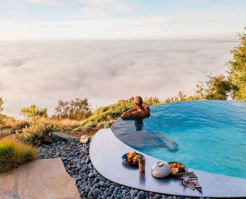 a woman sitting in a pool overlooking the ocean