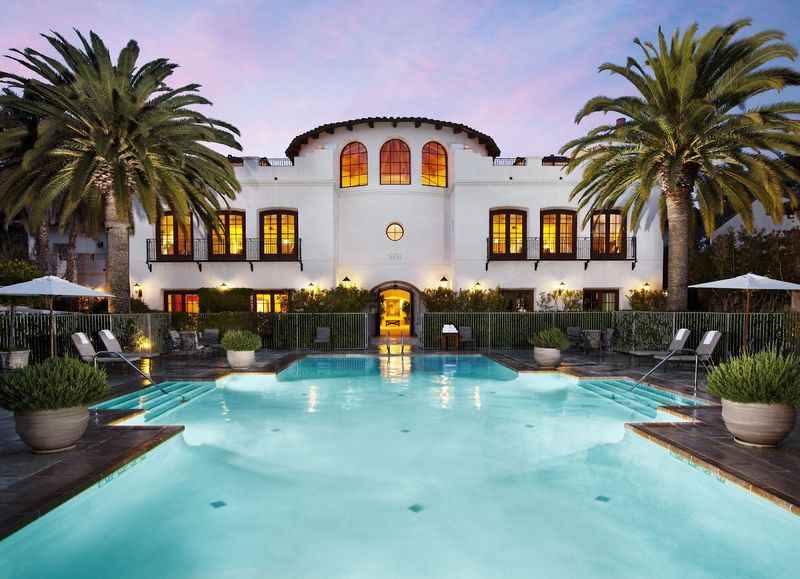 a pool with palm trees and a white house