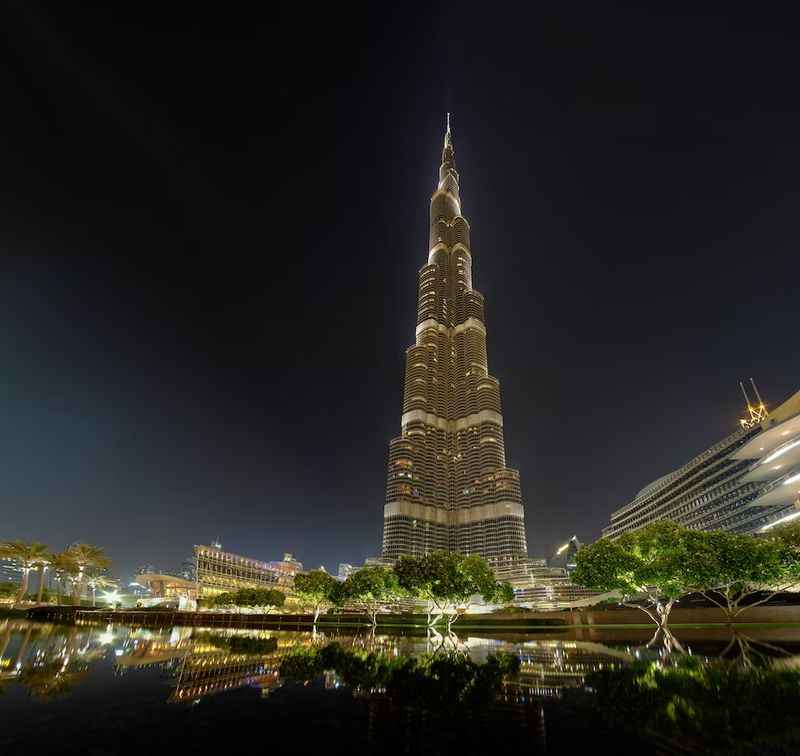 tower building with lights reflects on the water at night