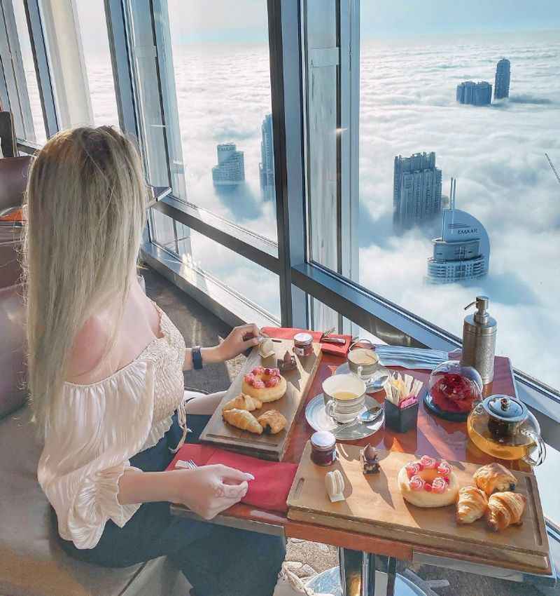 a woman sitting at a table with a view of the city