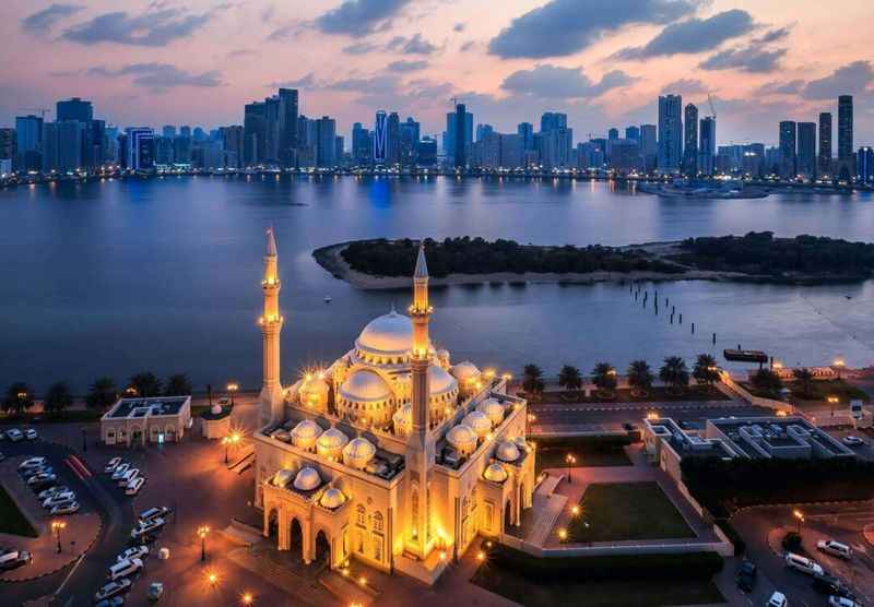 Aerial view of the emirate of Sharjah with mosque lit up at dusk