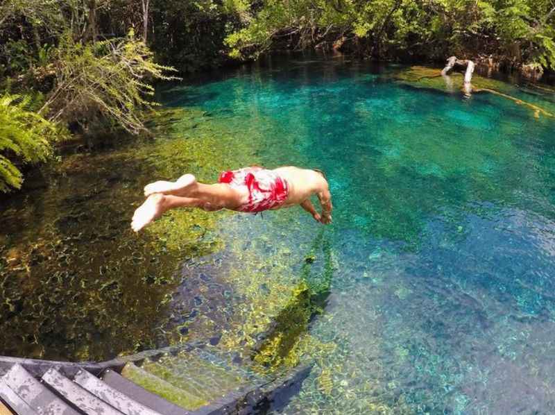 a man jumping into a clear blue pool