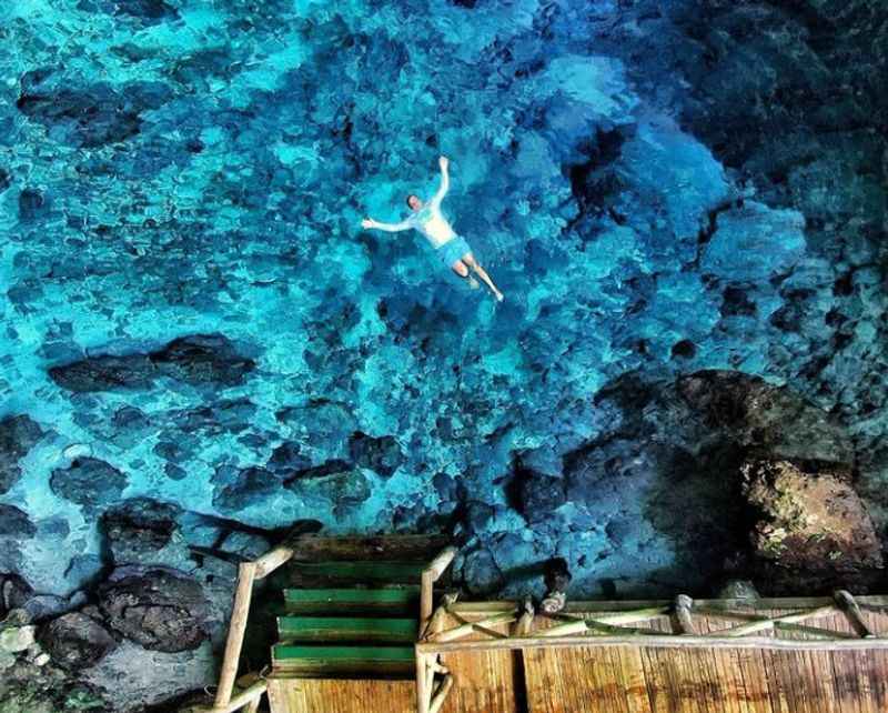 a person swimming in a blue cave