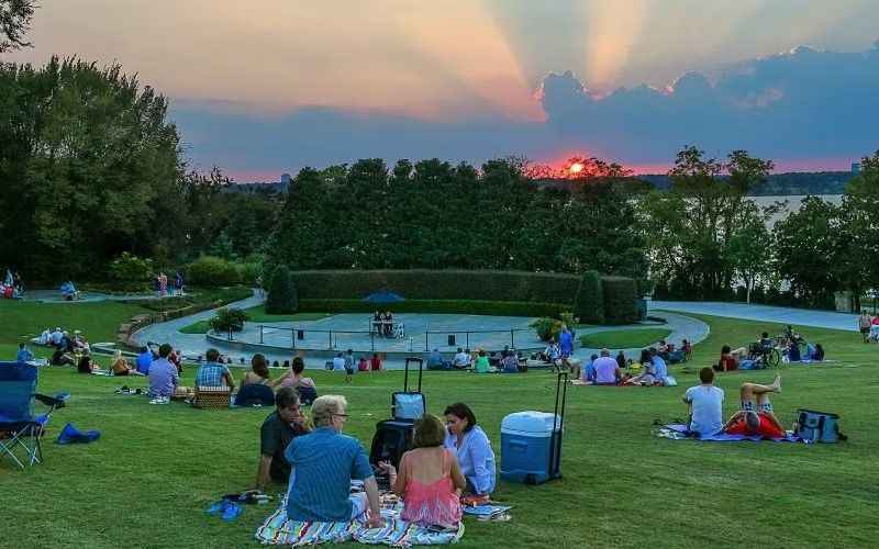 people sitting on the grass watching the sunset