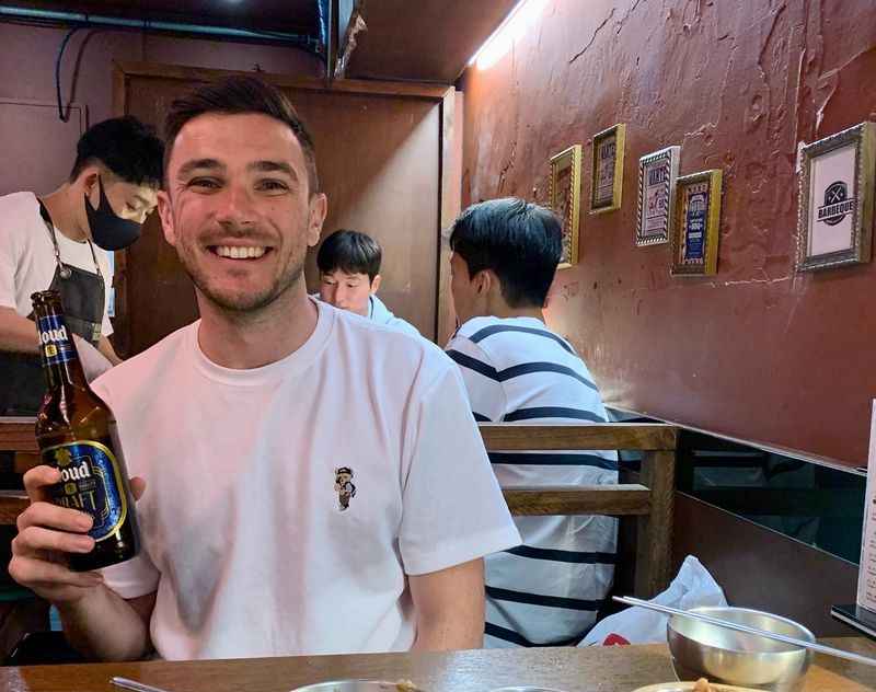 a man sitting at a table with a bottle of beer