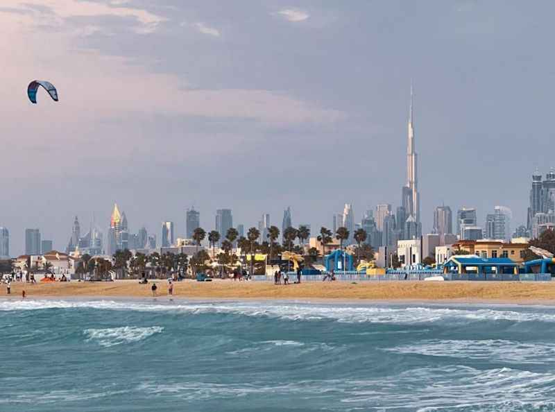 kite flying over the beach with a city in the background