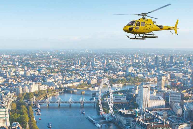 helicopter flying over central London with buildings and river below