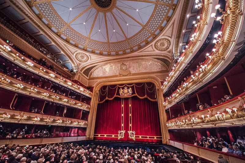 Large hall filled with people with red curtains