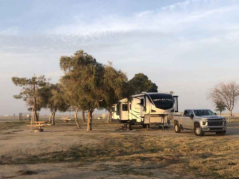 a truck parked next to a camper on a dirt road