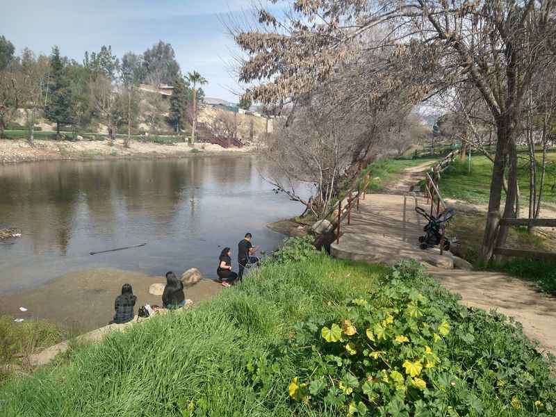 a couple of people sitting on a bench by a river