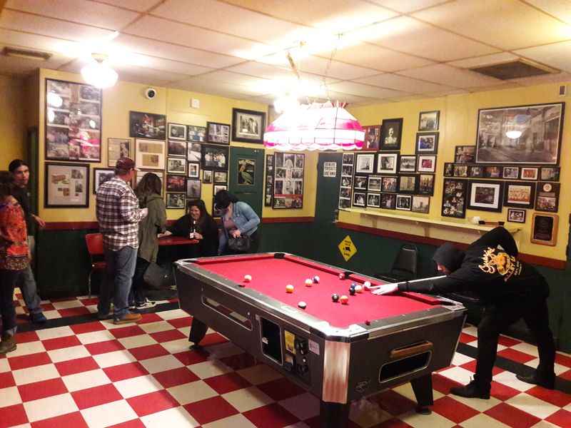 room with red and white tiles people playing pool