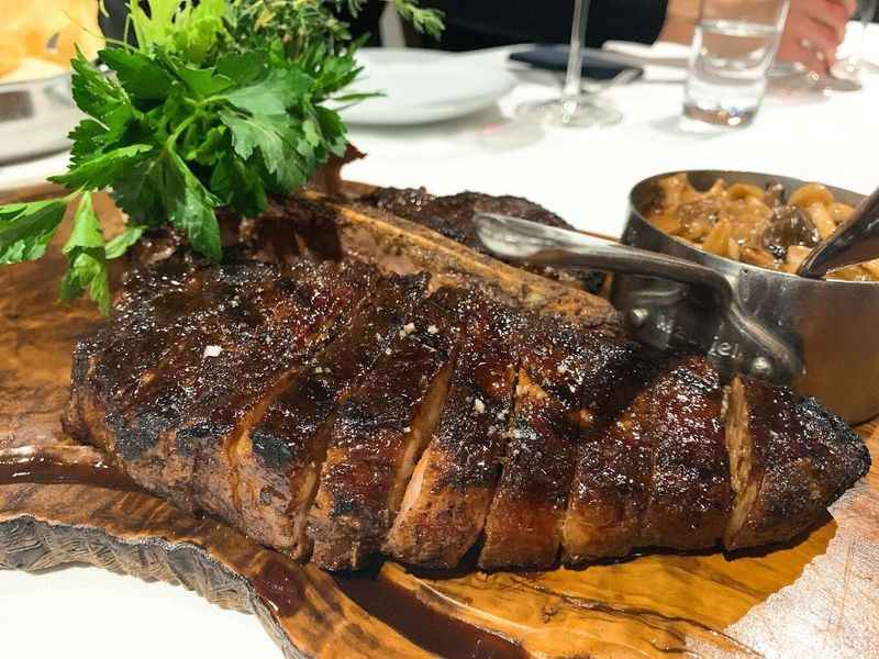 a steak on a wooden board with a knife and fork