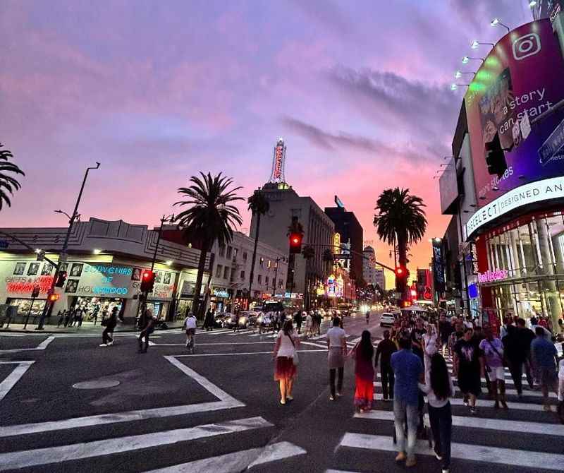 people walking across a crosswalk at sunset