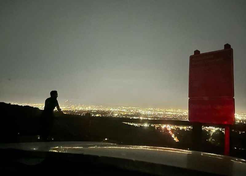 a person standing on a roof looking at the city lights