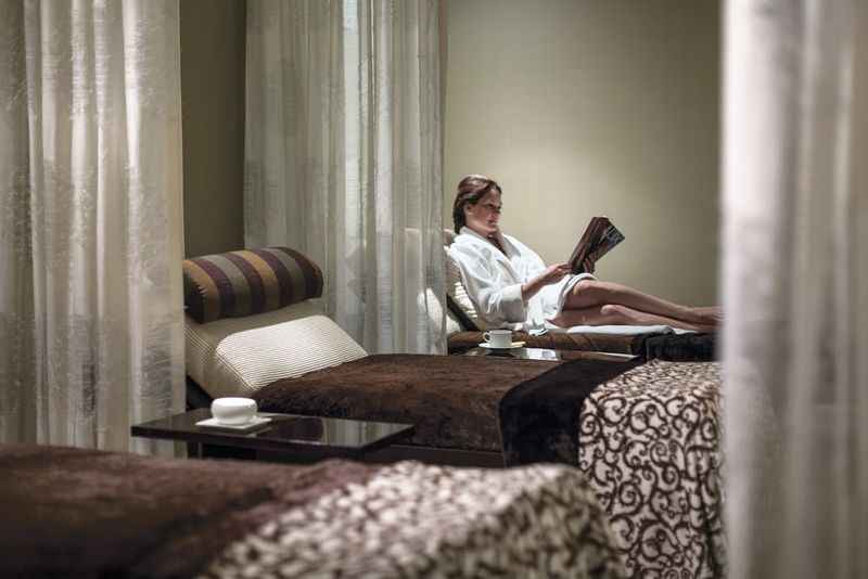 a woman sitting in a massage room with a book