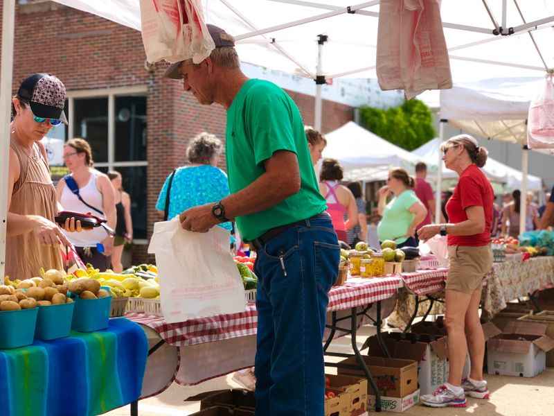 a man and woman standing under a tent selling fruit