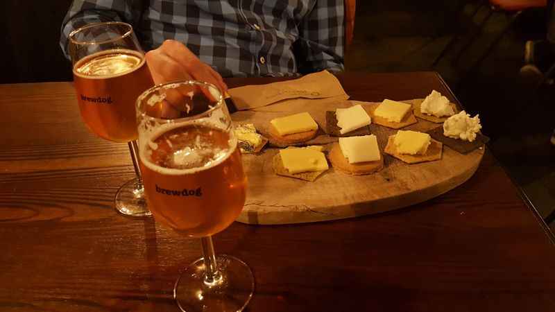 table with a plate of cheese and glass of beer