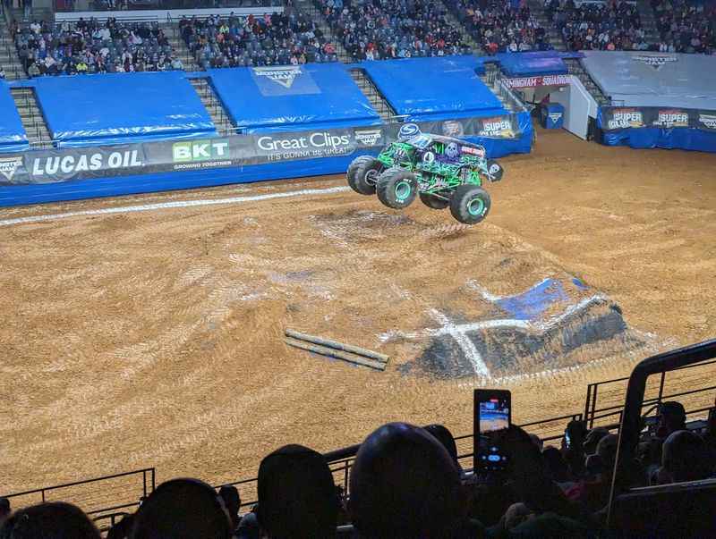 a monster truck is racing in a dirt pit