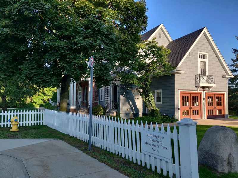 a white picket fence surrounds the front of a gray house