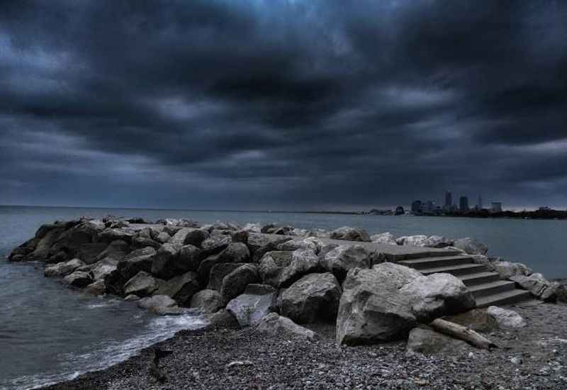 a dark sky over the water and rocks