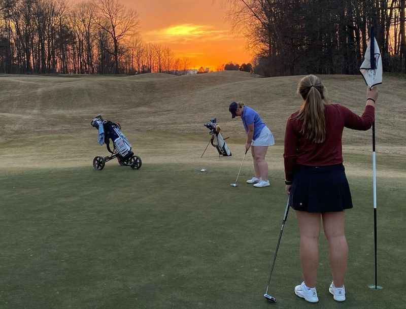 a woman playing golf at sunset