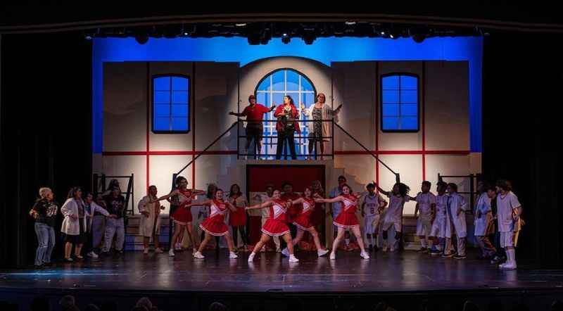 a group of people on stage singing and dancing together