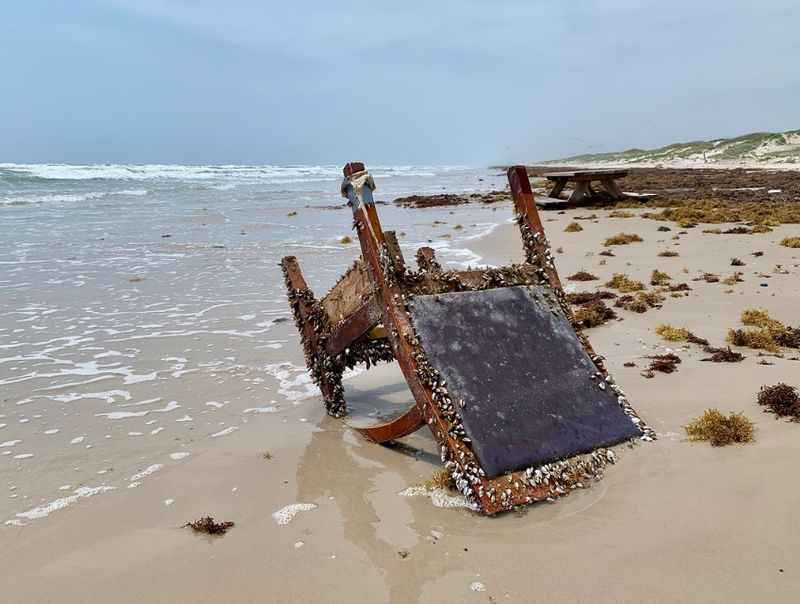 upside-down rusty chair on the beach