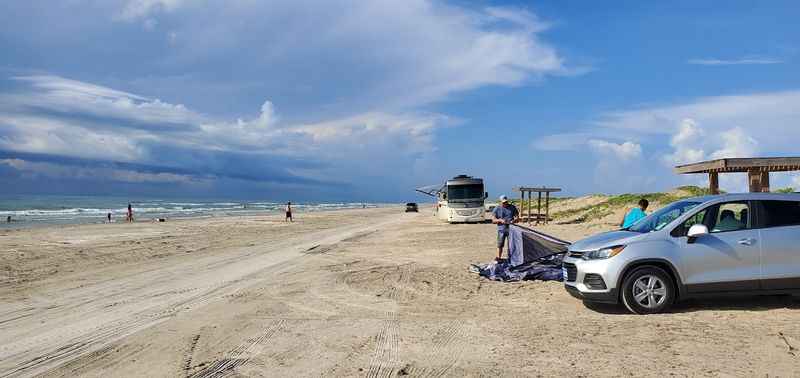 a car parked on the beach next to a boat