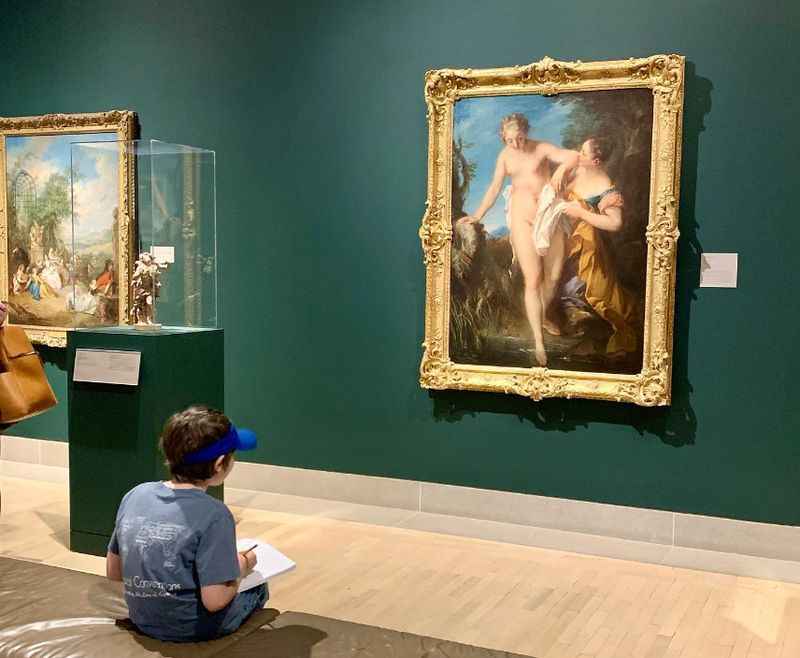 woman sitting on the floor in front of paintings