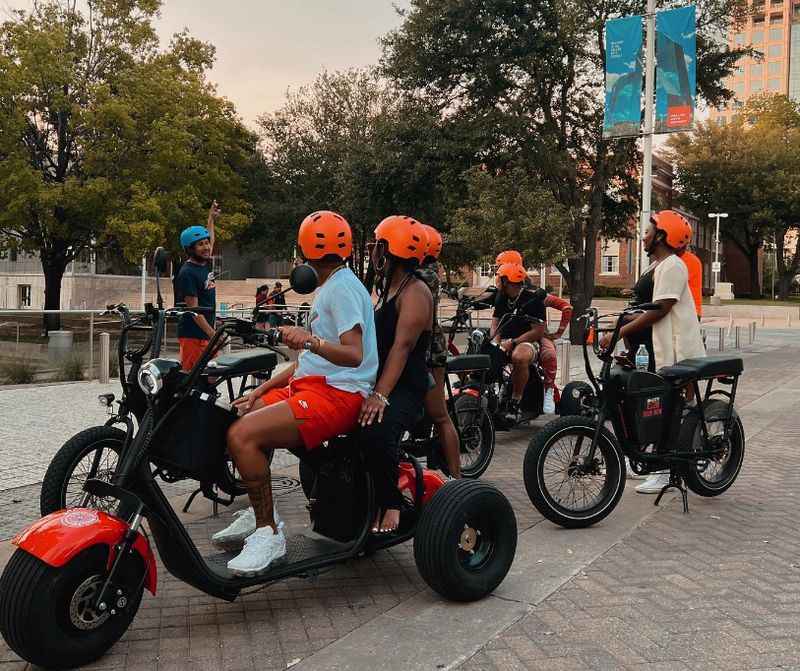 a group of people riding on three wheeled scoots