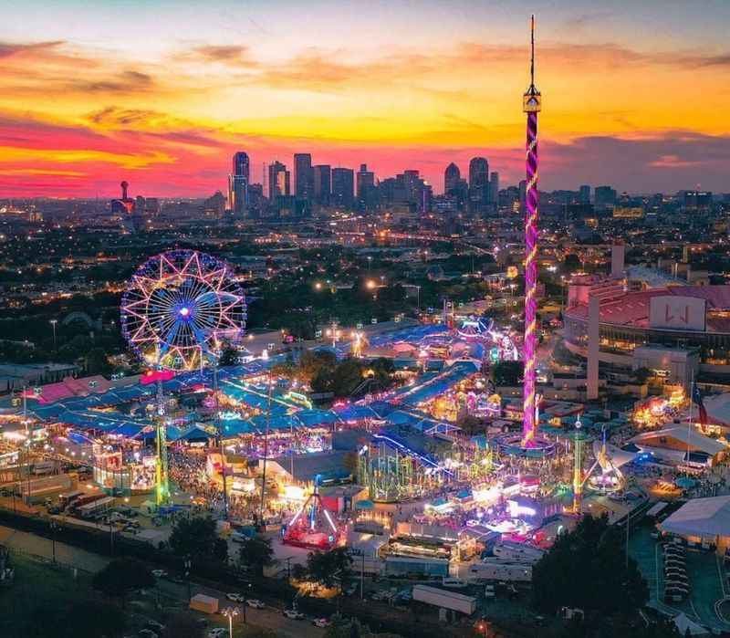 a carnival at sunset with the city skyline in the background