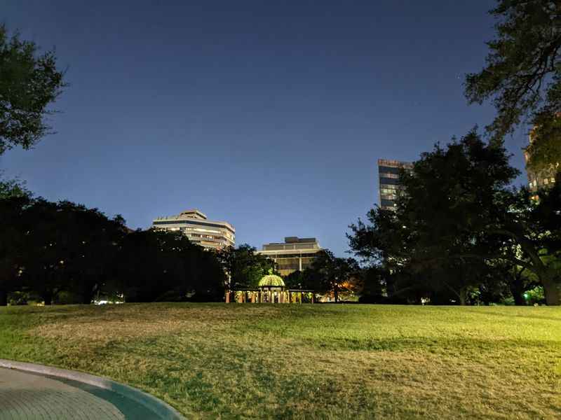 a park with a fountain and a building in the background