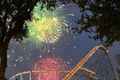 fireworks are lit up the sky above a roller coaster