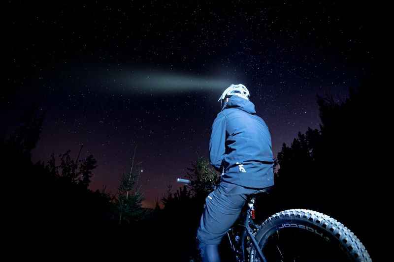 a man riding a bike at night with a starry sky