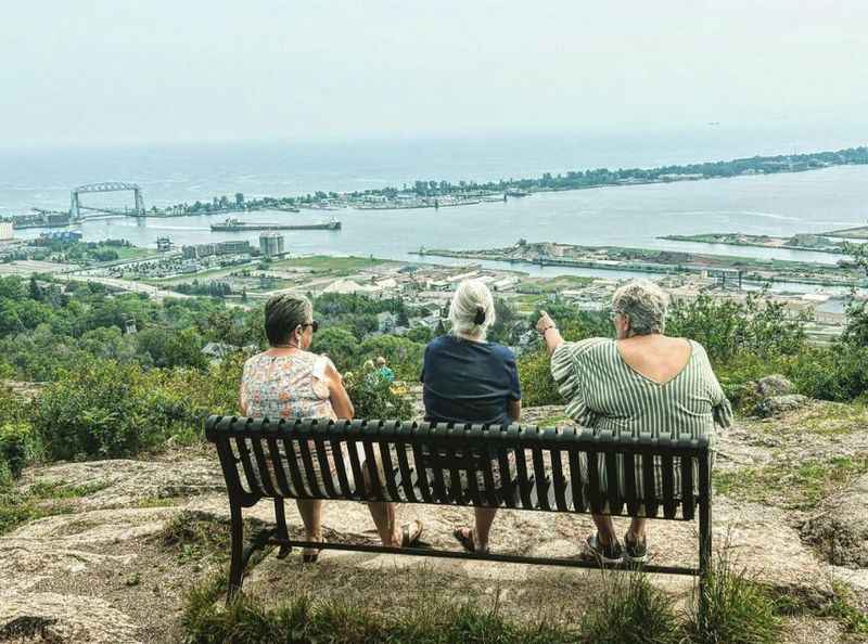 two people sitting on a bench overlooking the ocean