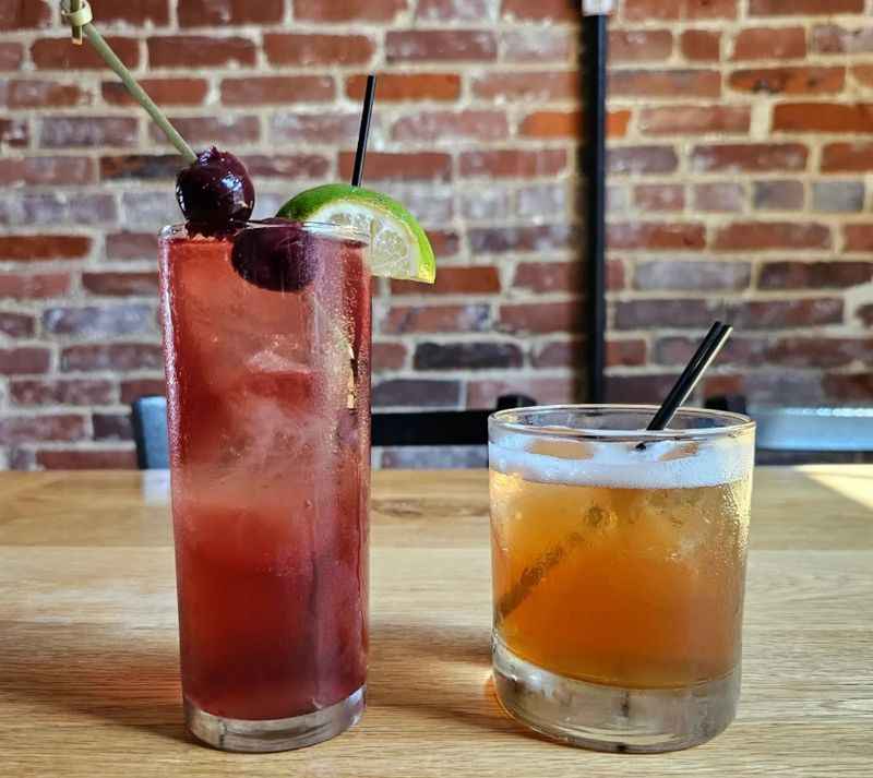 two cocktails on a table, one with cherry on top