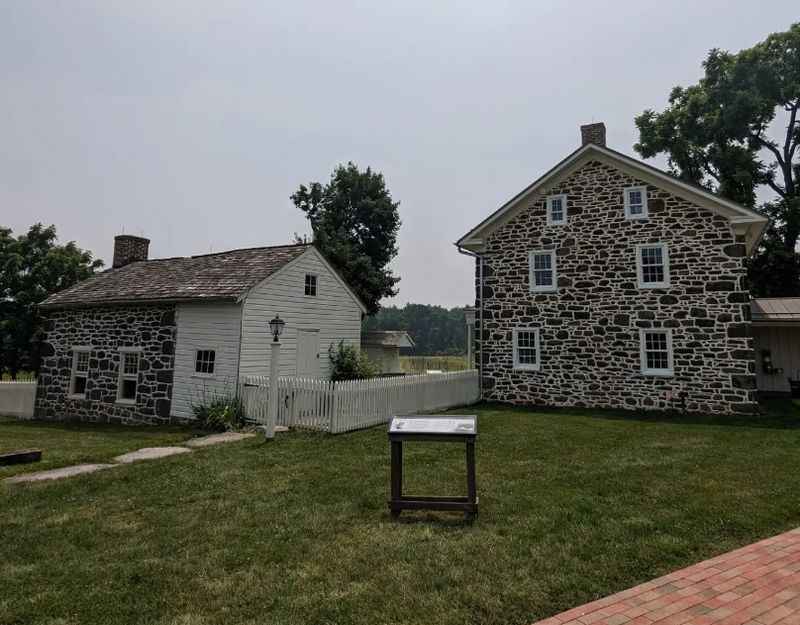 a stone house with a white picket and a brick walkway