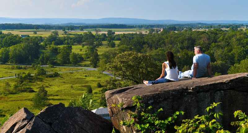 a couple sitting on a rock overlooking the valley