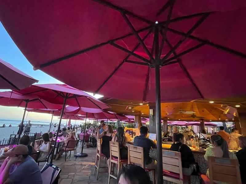 a group of people sitting at tables under umbrellas
