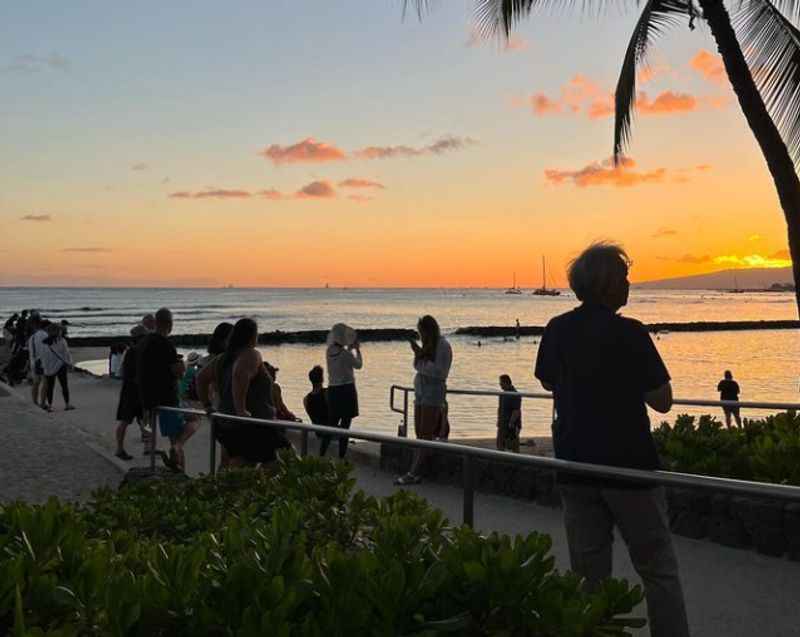 people walking along the beach at sunset