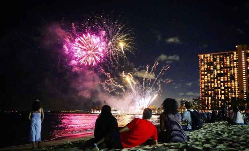 people watch fireworks on the beach in the evening