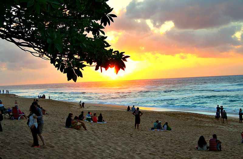 a group of people on a beach at sunset