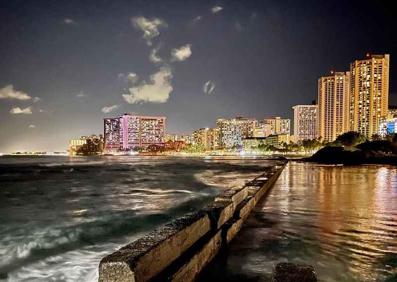 a city at night with the ocean and buildings