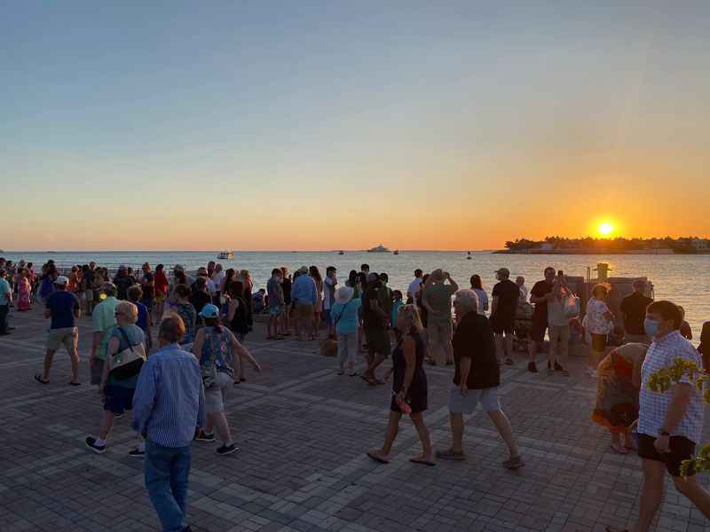 people walking along the water at sunset