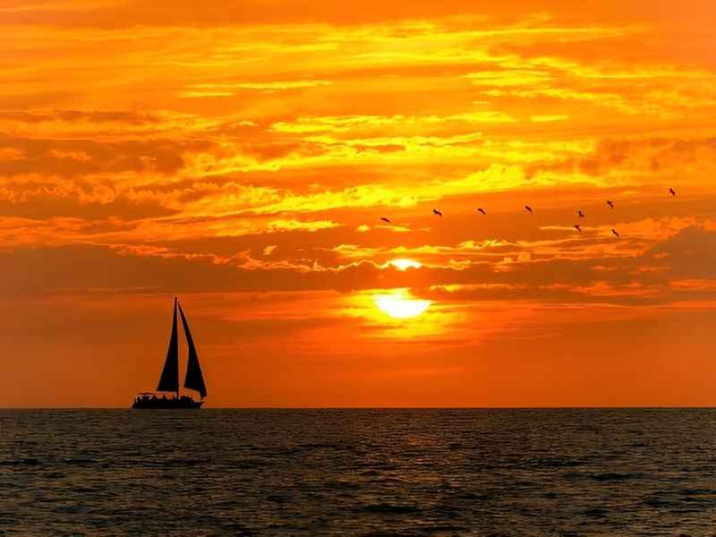 a sailer is sailing in the ocean at sunset