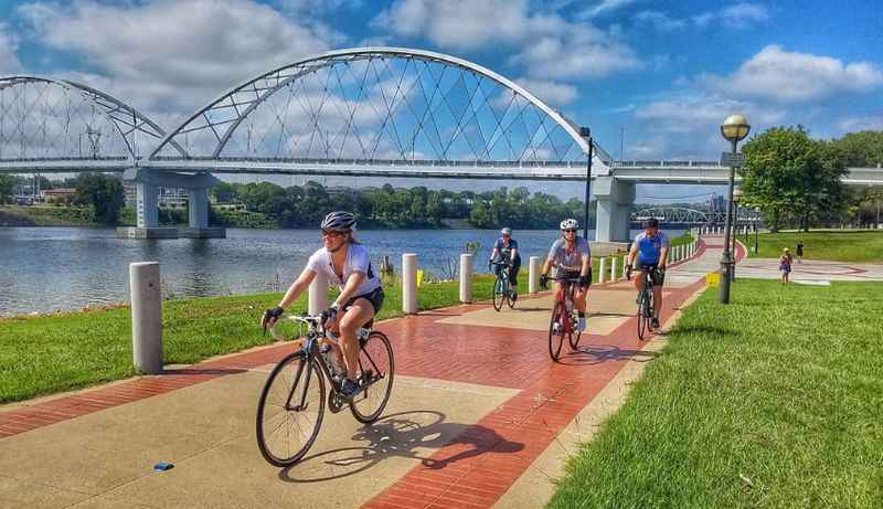 people riding bikes on the bike path near the river