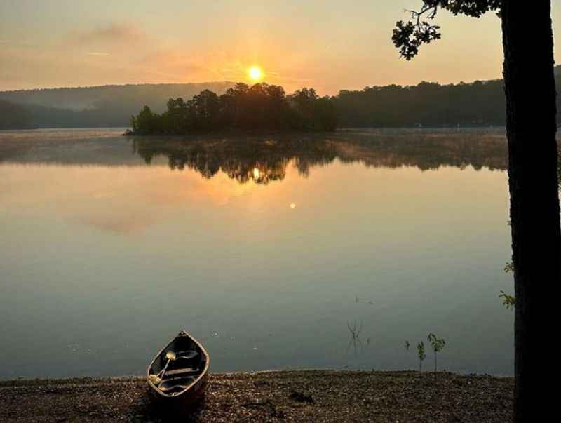 a boat sits on the shore of a lake