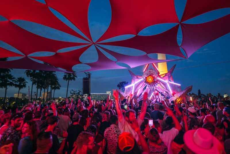 a crowd of people at a concert under a red umbrella